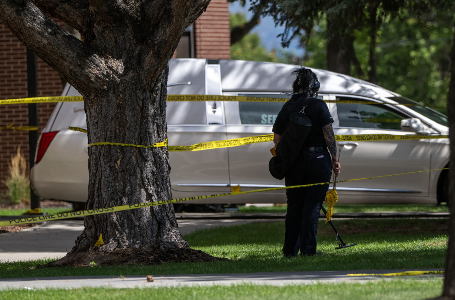A member of the Forensics Unit uses a metal detector to search for evidence as police investigate a shooting that occurred in Kearns during a funeral on Monday, Aug. 17, 2026. (Scott G Winterton, Deseret News)