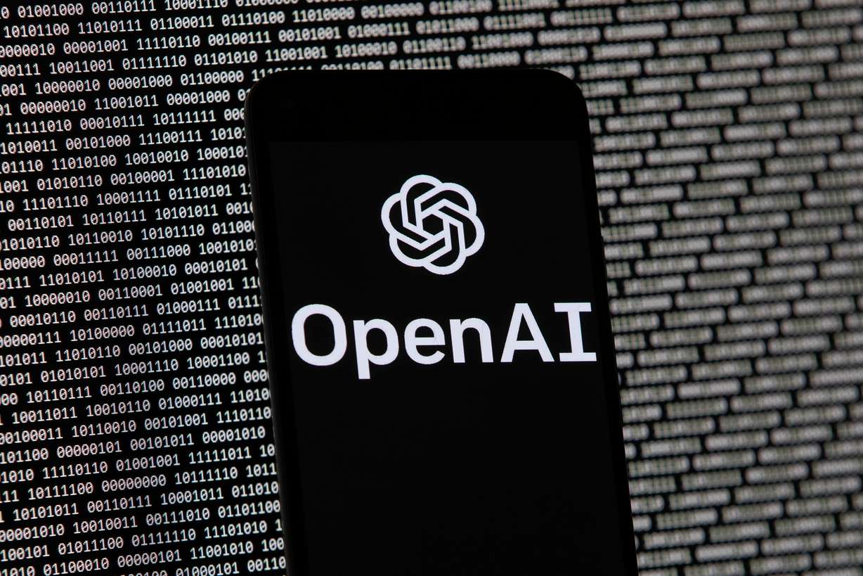 The OpenAI logo appears on a mobile phone in front of a computer screen with random binary data, March 9, 2023, in Boston. Rep. Celeste Maloy introduced an AI regulatory bill of her recently. (Photo: Michael Dwyer, Associated Press)