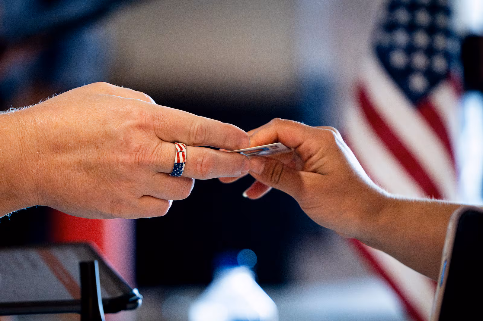 A poll worker hands a voter back their driver's license as part of Utah’s primary election at Cen...